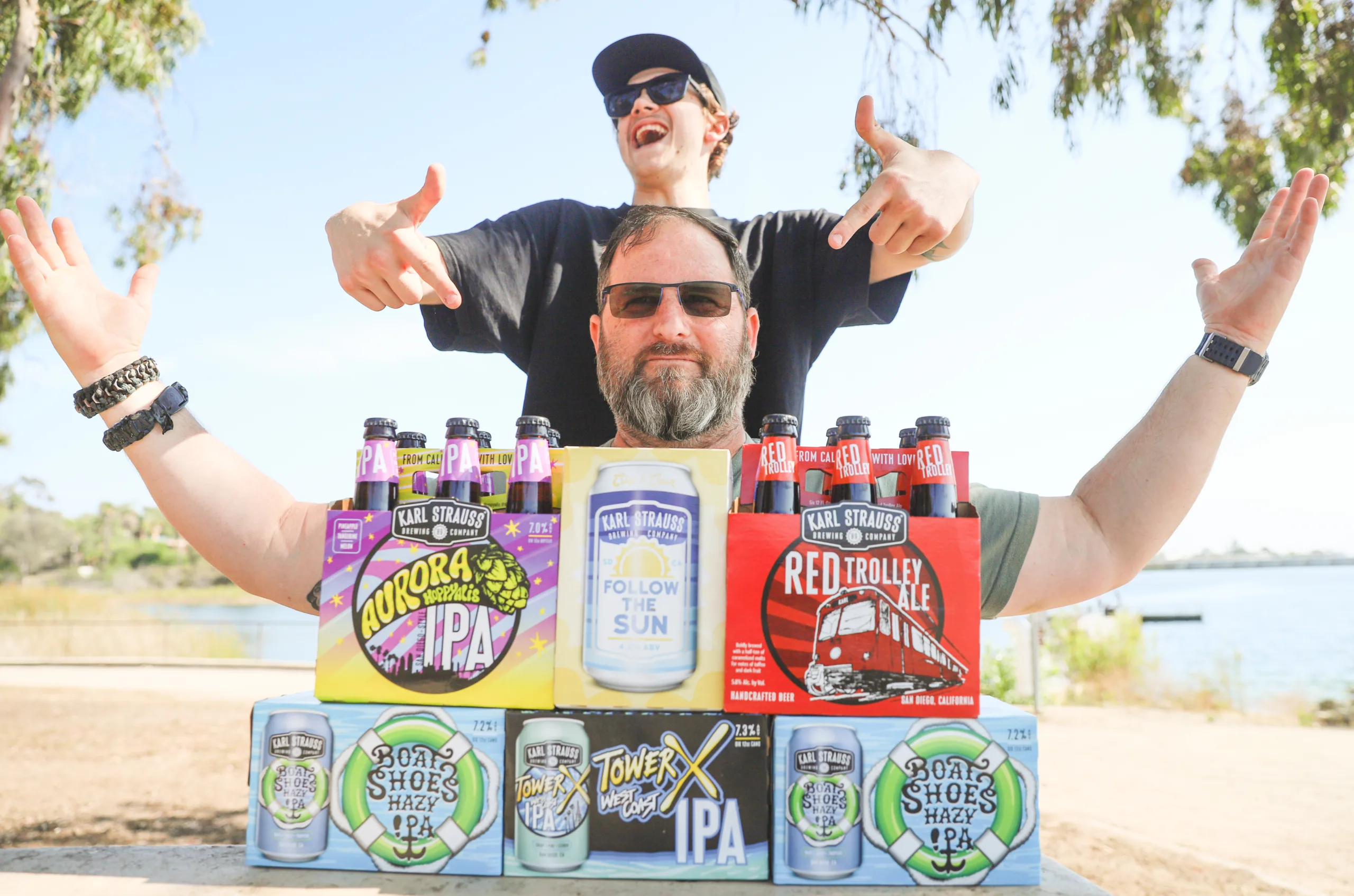 A young and older man standing in front of a box of beer